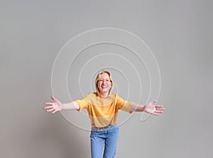 Portrait of ecstatic young blond businesswoman with arms outstretched standing on white background