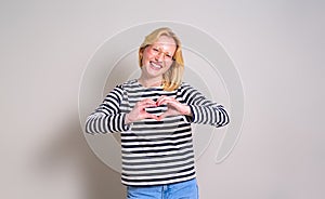 Portrait of ecstatic young woman gesturing heart shape and smiling at camera on white background