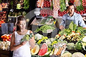 Portrait of male shop assistant and female customer choosing broccoli in vegetable shop photo