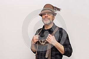 Portrait of an elderly Austrian man 50-55 years old wearing a Tyrolean hat and leather shorts on a white background.