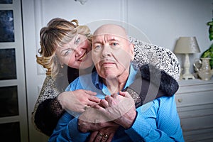 Portrait of an elderly bald man and fat plump woman in a blue dress in a nice room. Old pensioner father and adult