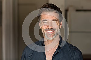 A portrait of a elderly bearded man smiling at the camera. He is a happy man.