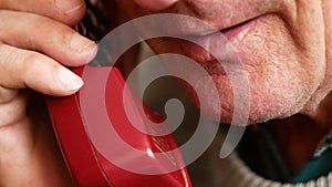 Portrait of an elderly Caucasian man talking on his home phone. A pensioner over 70 communicates on the phone with family members.