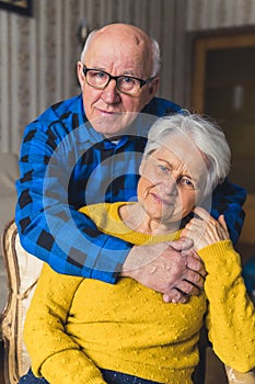 Portrait of an elderly couple - caring husband standing behind his happy loving wife and hugging her and a woman herself
