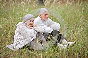 Portrait of elderly couple sitting in autumn nature