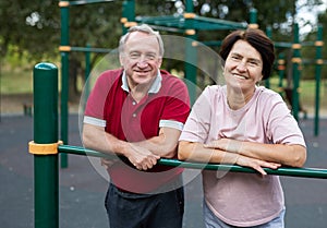 Portrait of an elderly couple in sportswear on sports ground in a city park on summer day