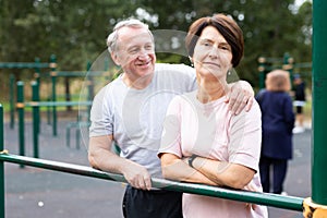 Portrait of an elderly couple in sportswear on sports ground in a city park on summer day