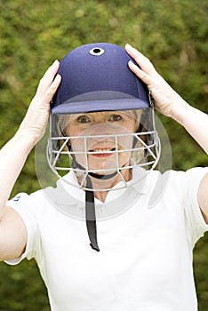 Portrait of an elderly female cricketer adjusting helmet