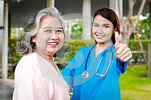 Portrait of an elderly female patient and a surgeon, both smiling brightly, standing outside a building.