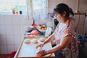 Portrait of an elderly latin woman cooking homemade bread in her kitchen