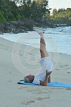 Portrait of elderly man doing yoga by the sea