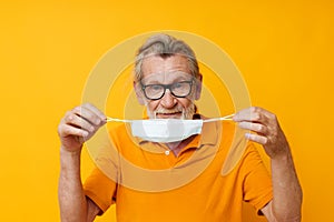 Portrait elderly man medical mask on the face protection close-up yellow background