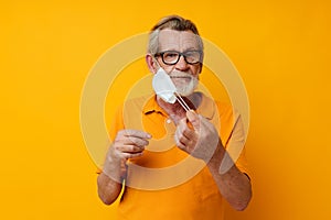 Portrait elderly man medical mask on the face protection close-up yellow background