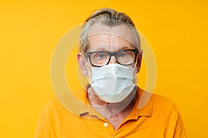 Portrait elderly man medical mask on the face protection close-up yellow background