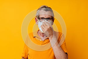 Portrait elderly man medical mask in a yellow shirt yellow background