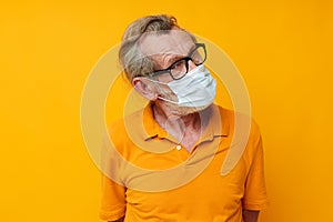 Portrait elderly man medical mask in a yellow shirt yellow background