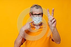 Portrait elderly man medical mask in a yellow shirt yellow background
