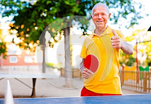 Portrait of elderly man with rackets for table tennis showing thumb up