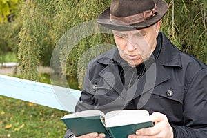 Portrait of an elderly man reading outdoors