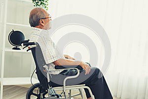 Portrait of an elderly man in a wheelchair contented and alone at home. photo
