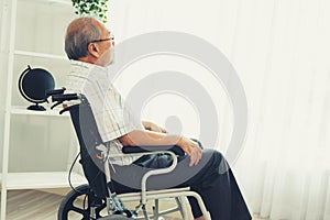 Portrait of an elderly man in a wheelchair contented and alone at home.