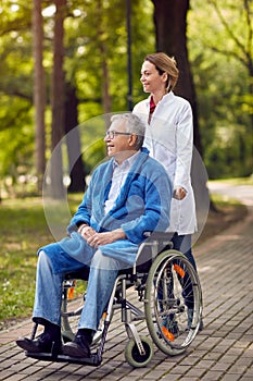 Portrait of elderly man on wheelchair with nurse outdoor