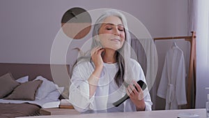 Portrait elderly mature middle-aged lady old 50s aged Caucasian woman in bathrobe morning beauty routine looking at