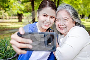 portrait of an elderly mother with her daughter Sit and relax on a bench in the park.