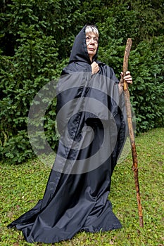 Portrait of an elderly nun 60-65 years old in a black cassock on the light background of the wall.