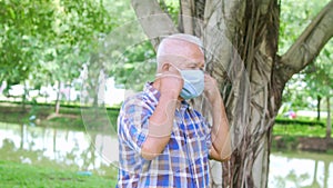 Portrait of Elderly old Asian man taking off face mask in the park after The epidemic situation resolved after There are vaccines