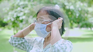 Portrait of Elderly old Asian woman taking off face mask in the park after The epidemic situation resolved after There are