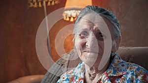 Portrait of an elderly woman 80-90 years old at home. Old odd lady with wrinkled skin face looking at camera. Detailed