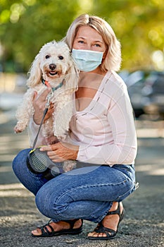 Portrait elderly woman with a dog outdoors an antivirus mask