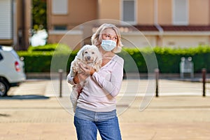 Portrait elderly woman with a dog outdoors an antivirus mask