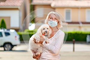 Portrait elderly woman with a dog outdoors an antivirus mask