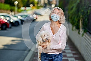 Portrait elderly woman with a dog outdoors an antivirus mask