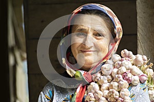 Portrait of an elderly woman having bunch of garlic toots on her shoulder