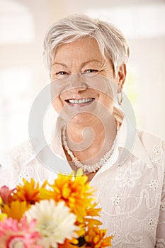Portrait of elderly woman holding flowers
