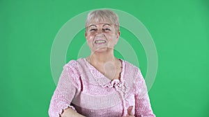 Portrait elderly woman looking at camera and showing thumbs up gesture. Gray haired grandmother with short hair in a