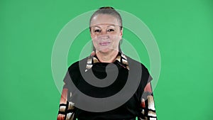 Portrait elderly woman looking at the camera and smiling. Brunette granny in black dress on green screen at studio