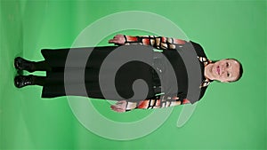 Portrait elderly woman looking at the camera and smiling. Brunette granny in black dress on green screen at studio. Slow