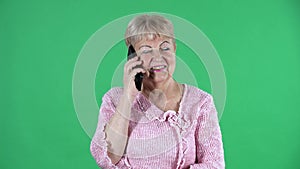 Portrait elderly woman looking at the camera and talking on her smartphone. Gray haired grandmother with short hair in a