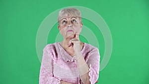 Portrait elderly woman thinking with concentration upset no idea. Gray haired grandmother with short hair in a pink