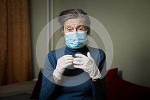 Portrait elderly woman took security measures, wearing gloves and medical mask, ahead of visit by social welfare workers during