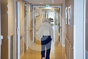 Portrait of elderly woman walking down hallway in retirement home background