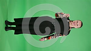 Portrait elderly woman is waving hand and showing gesture come here. Brunette granny in black dress on green screen at