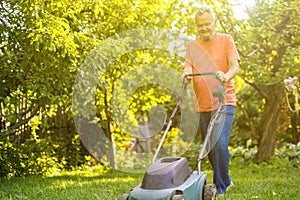 Portrait of eldery senior man working in the summer garden walking on a grass field