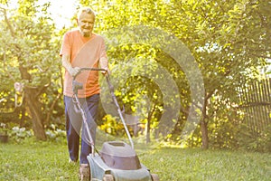 Portrait of eldery senior man working in the summer garden walking on a grass field