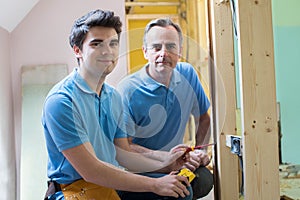 Portrait Of Electrician With Apprentice Working In New Home