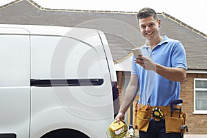 Portrait Of Electrician Checking Message On Mobile Phone